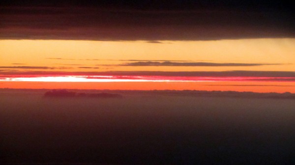 A rare view: Sunlit high-altitude clouds in the distance, seen between two layers of clouds nearby